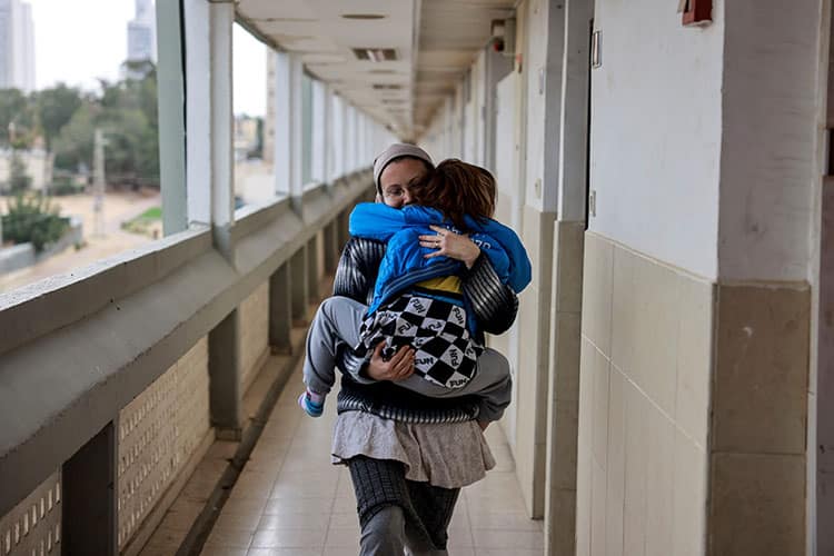 Woman carrying a child down a hallway